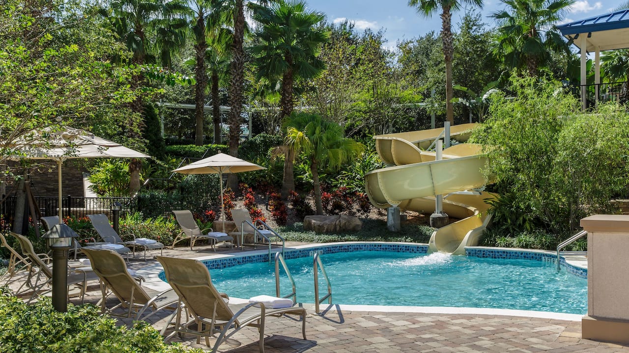 Grotto Pool and water slide with lounge chairs and umbrellas