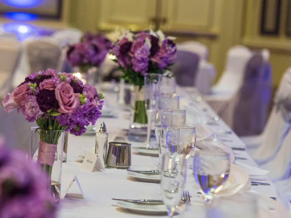 Wedding table set up with place setting and purple flower bouquets