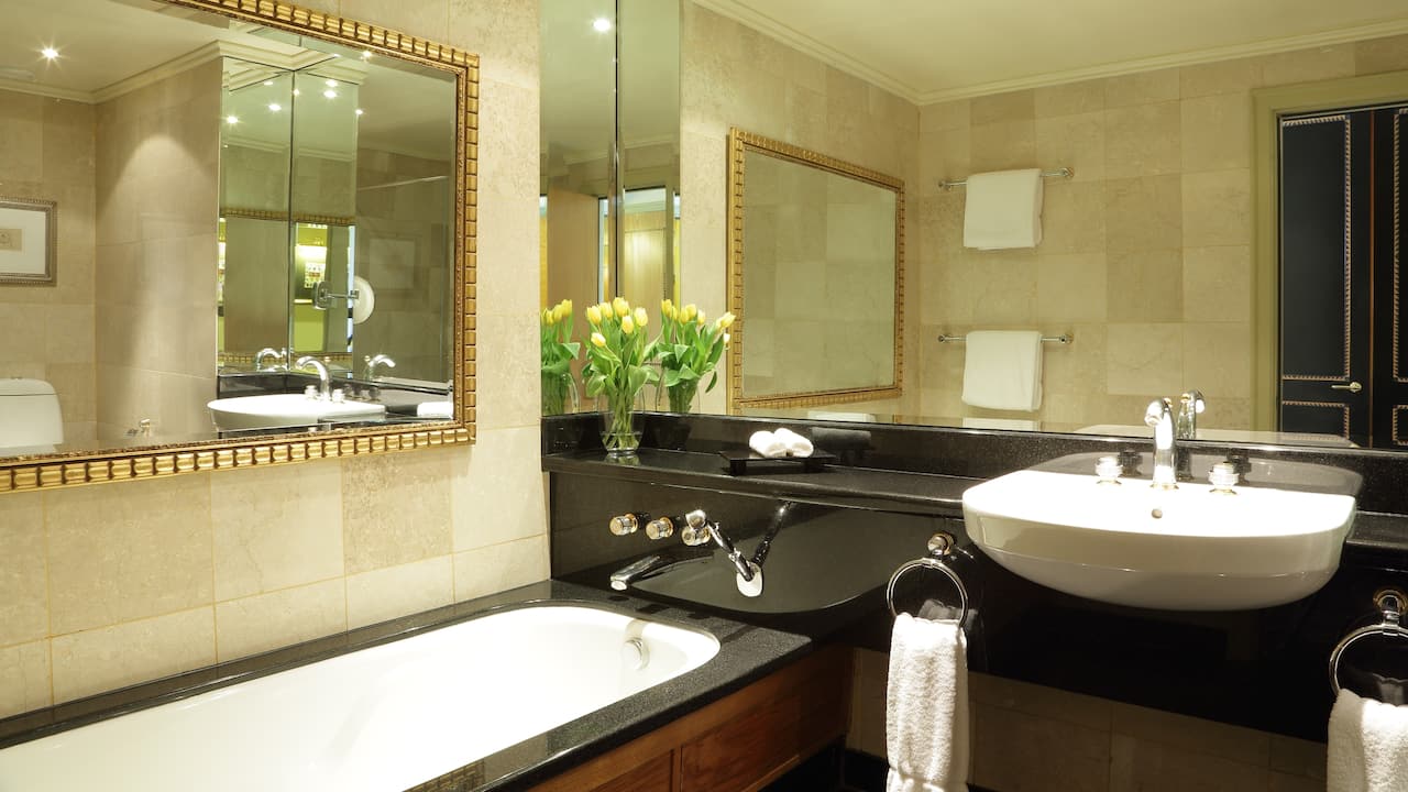 Standard room bathroom with bathtub, sink, and large vanity mirror