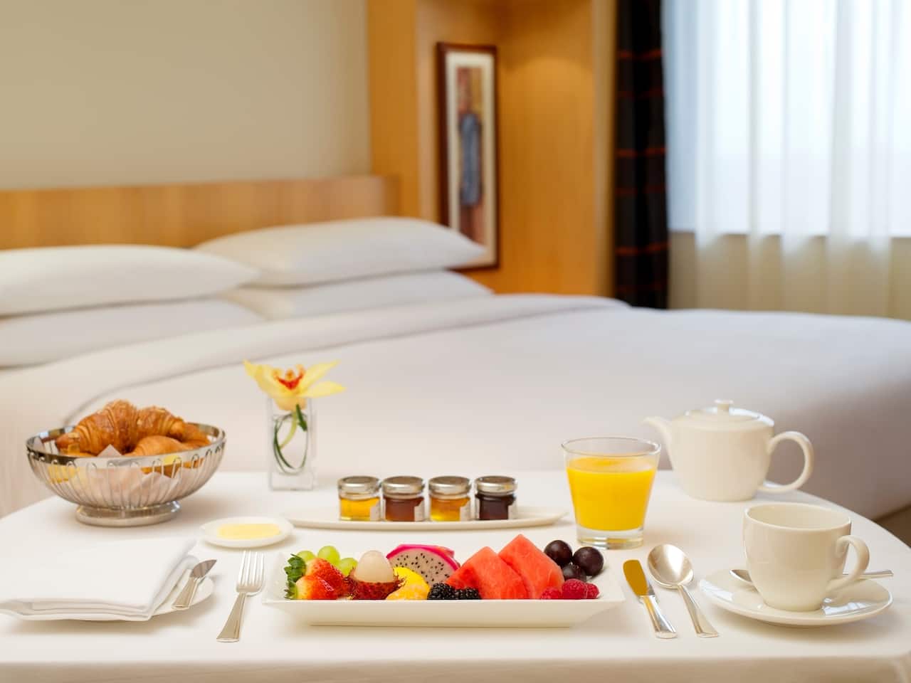 King-sized bed and room service tray by large window in hotel suite
