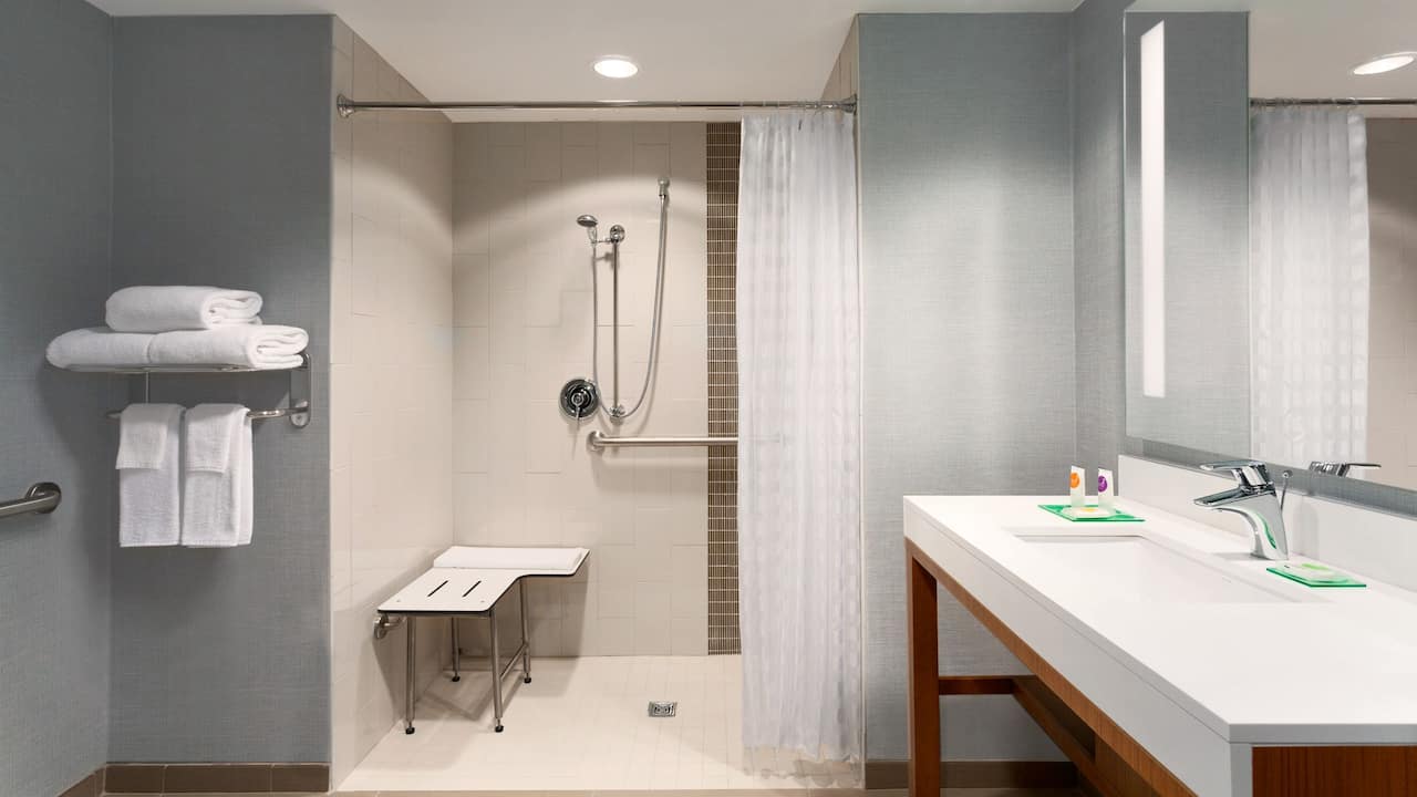 Omaha hotel bathroom with roll in shower that has seating and grab bars at Hyatt Place Omaha / Downtown Old Market