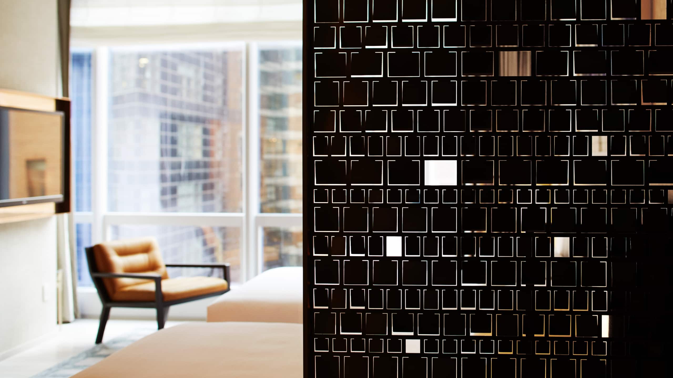 Two beds and a side chair behind a privacy screen with floor to ceiling windows and a city view