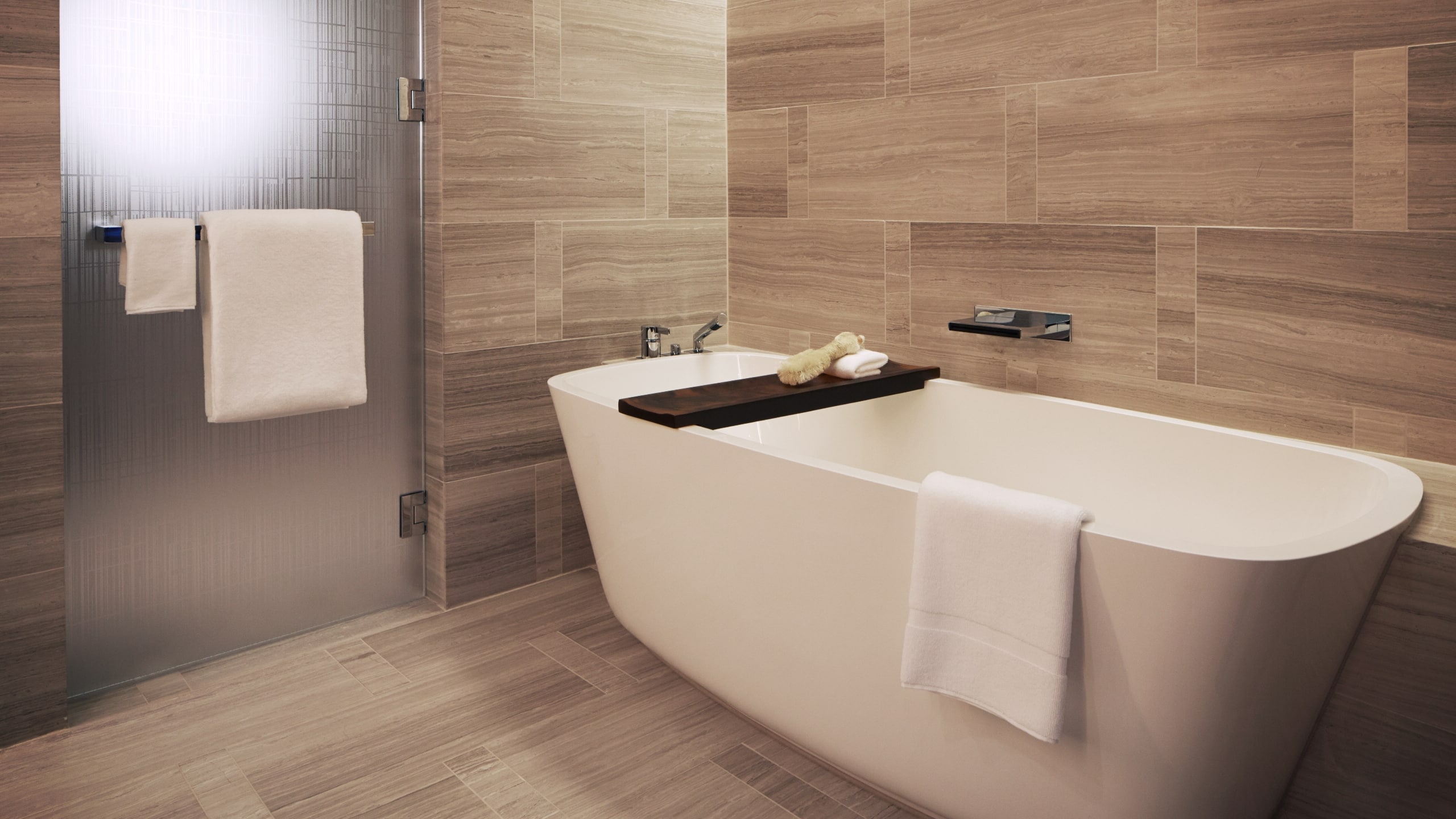 2 of 3 A freestanding bathtub in a room with modern wood paneling