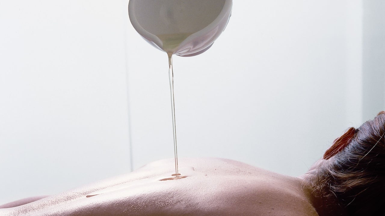 Masseuse pouring oil on a guest’s back during a treatment at Amanary Spa