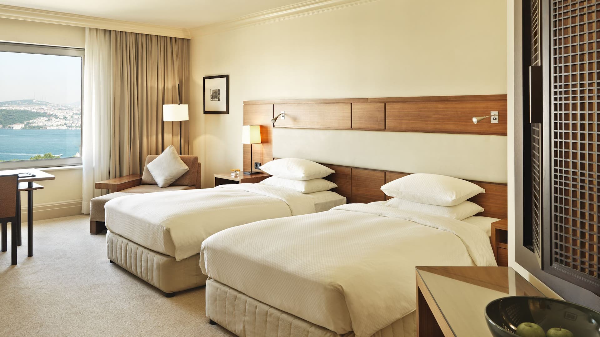 1 de 5 Luxury Istanbul hotel room with 2 twin beds at Grand Hyatt Istanbul, offering a workspace, cozy reading sofa, carpeted floors, and bathroom window views, all complemented by stunning Bosphorus views.
