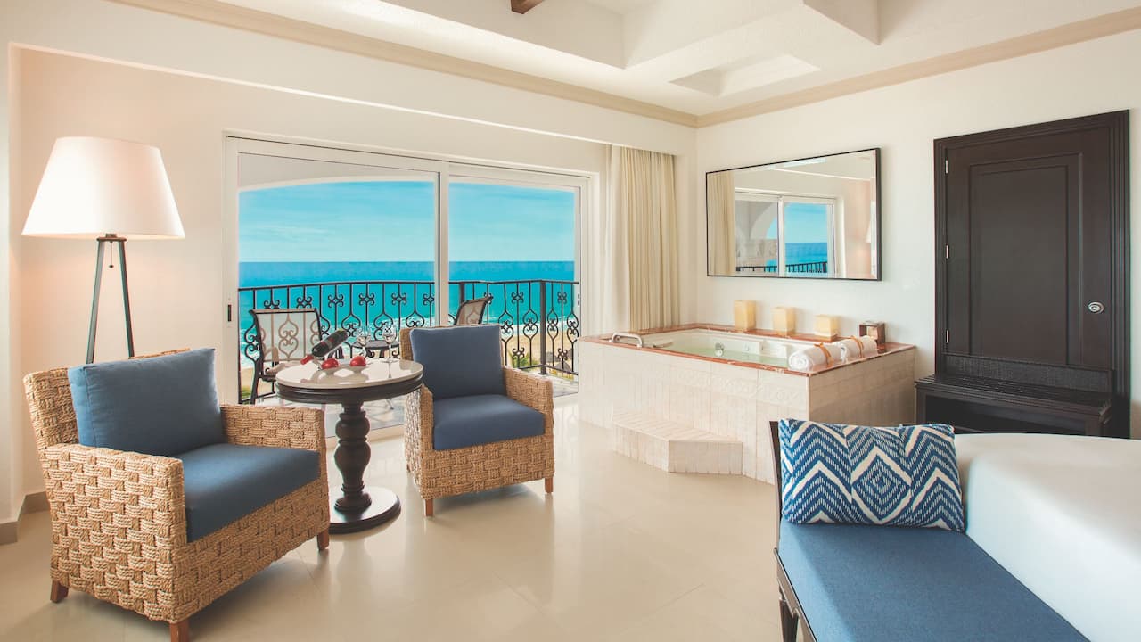 Bed and living area in resort suite with oceanfront view from patio