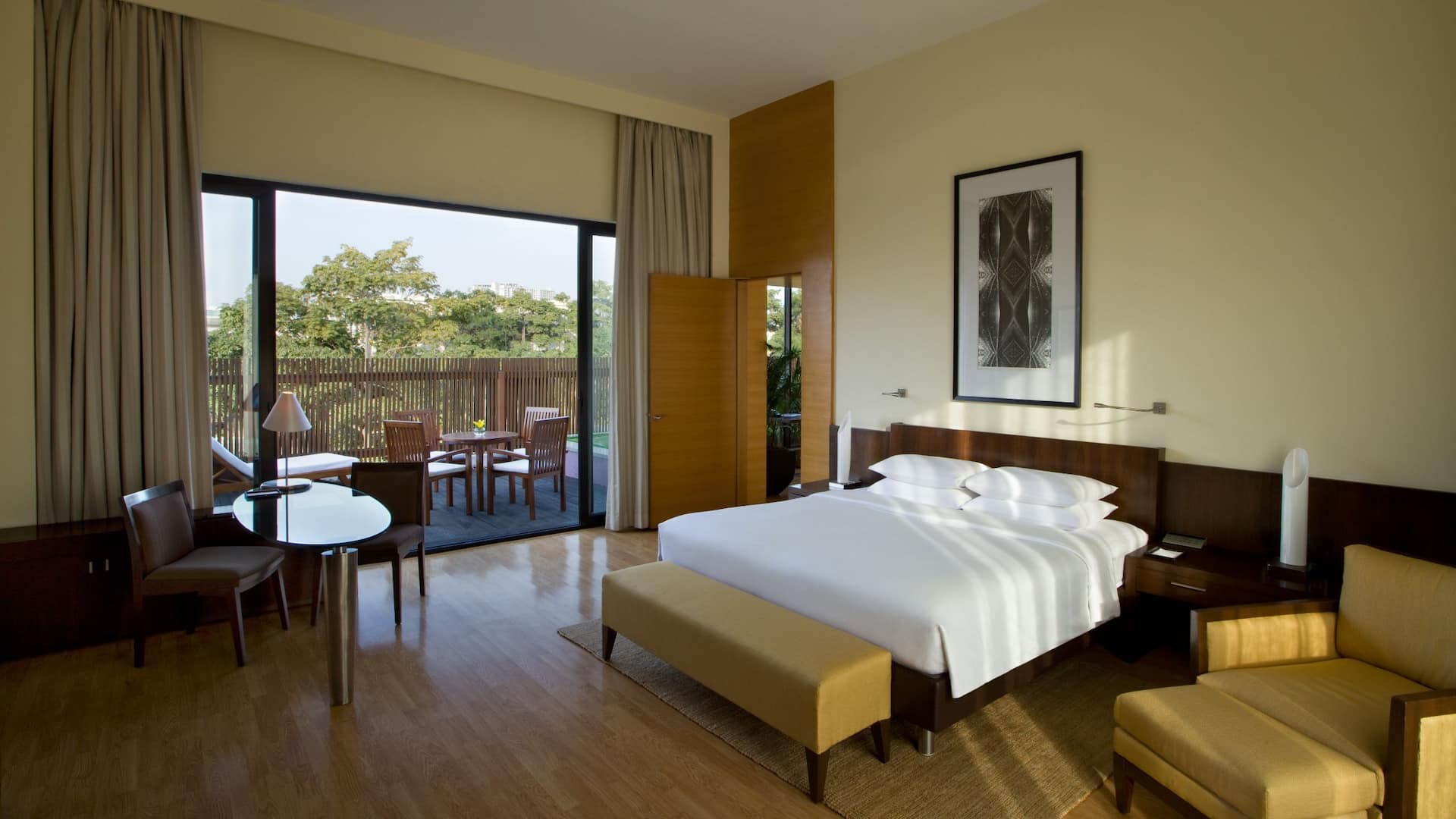 Wide Angle view of Hyatt Executive Suite with a king bed and partial view of terrace balcony having sitting space for 4 people