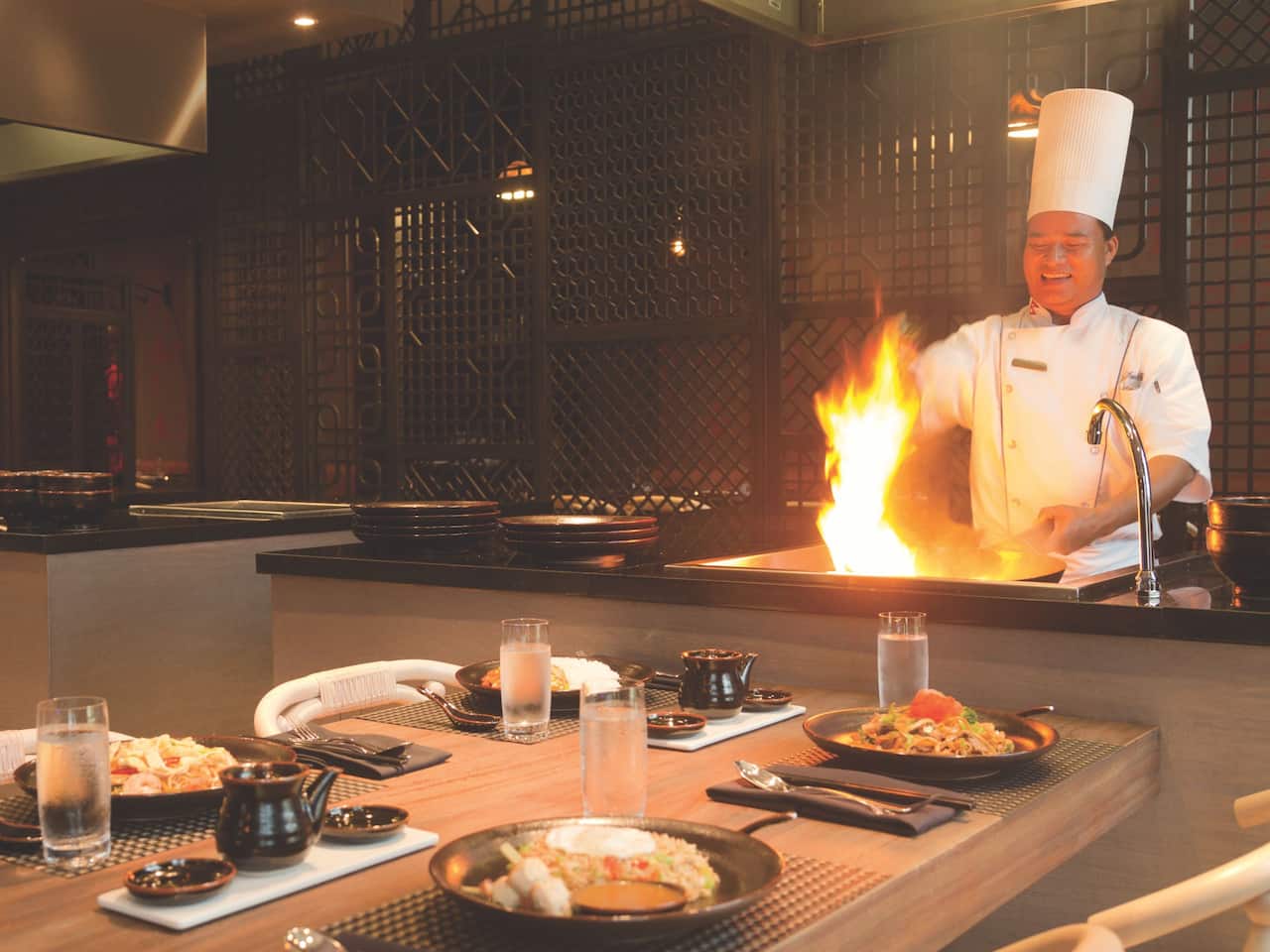 Chef cooking over open flame on restaurant grill in front of table at FuZion Asian Grill Hyatt Ziva Rose Hall
