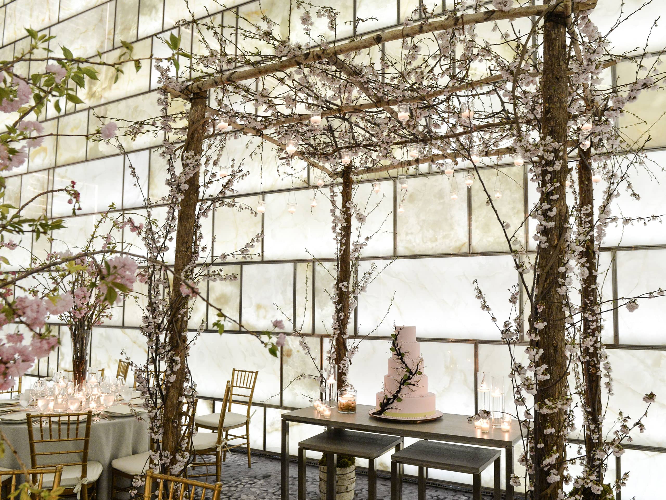 A wedding cake on a table under an trellis decorated in floral sprigs
