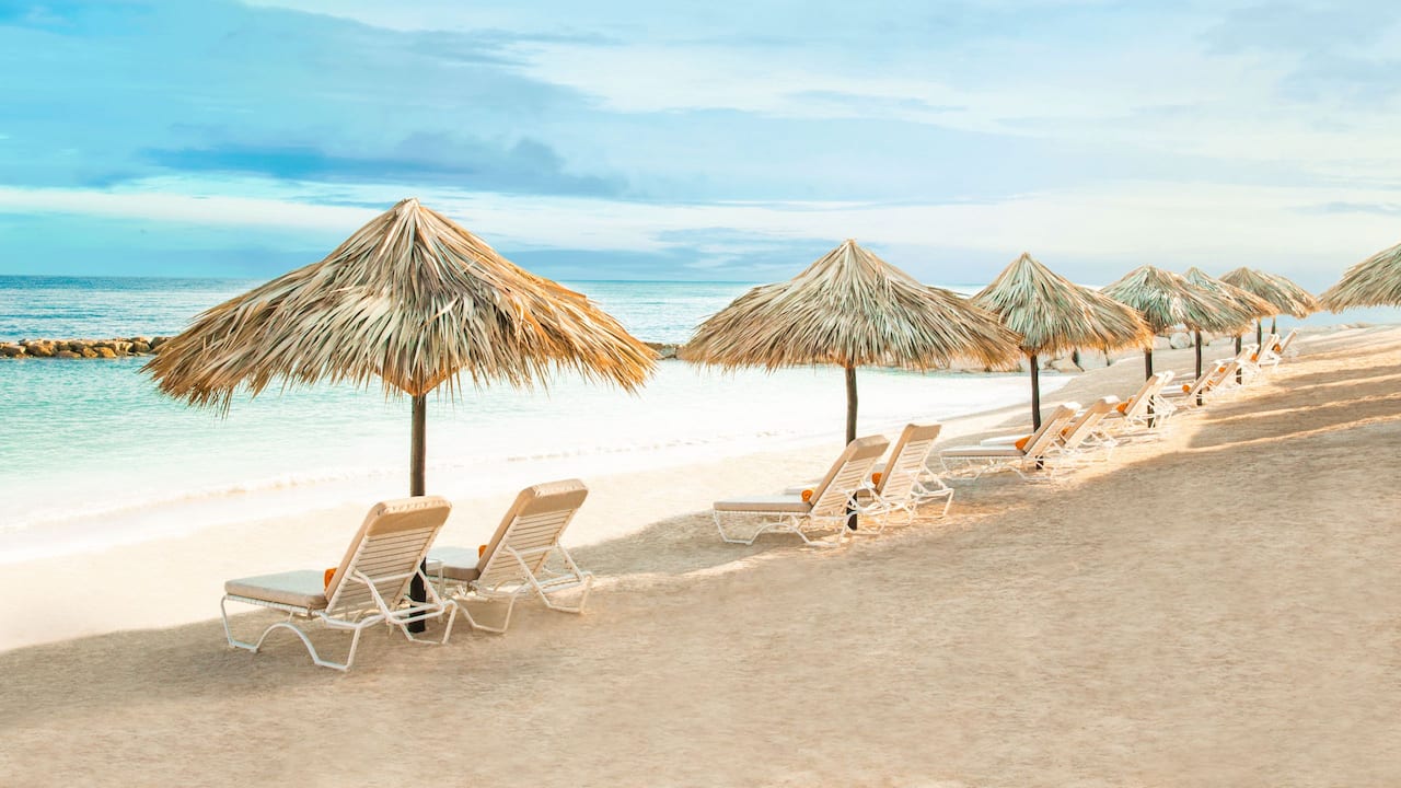 Sets of chairs under several tiki umbrellas on resort beach