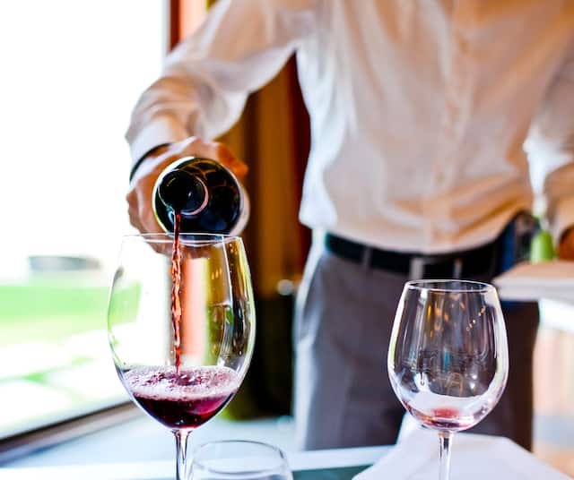 Server pouring red wine into glass