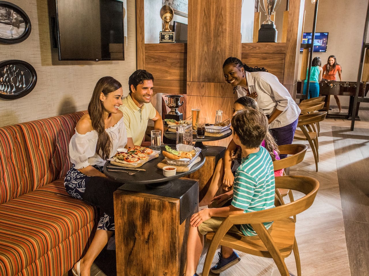 Waitress speaking with family seated at table with meals in Union Jackz Restaurant at Hyatt Ziva Rose Hall