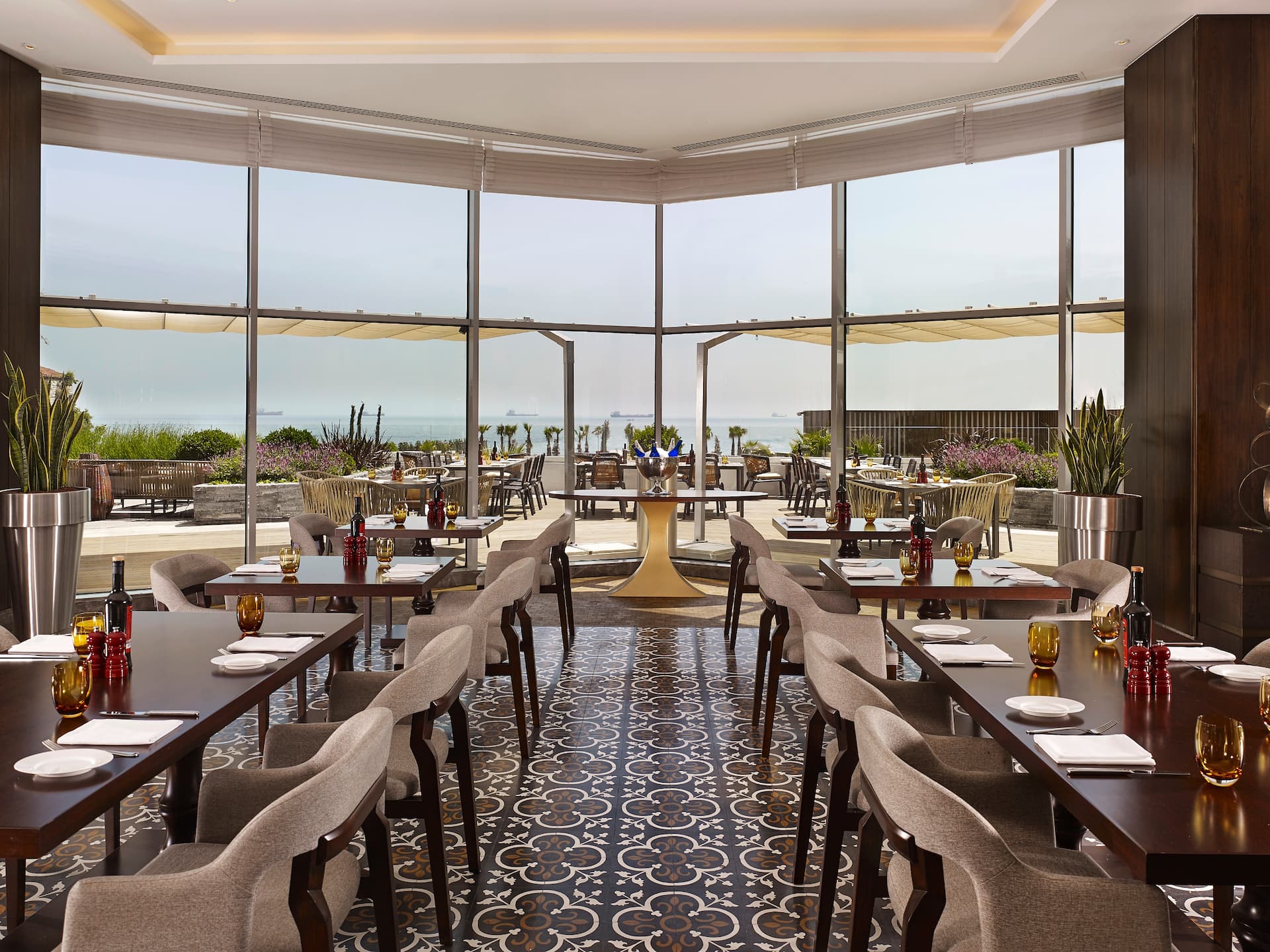 Stylish restaurant at Hyatt Regency Istanbul Ataköy with floor-to-ceiling windows, elegant dining tables, and a terrace overlooking the sea.