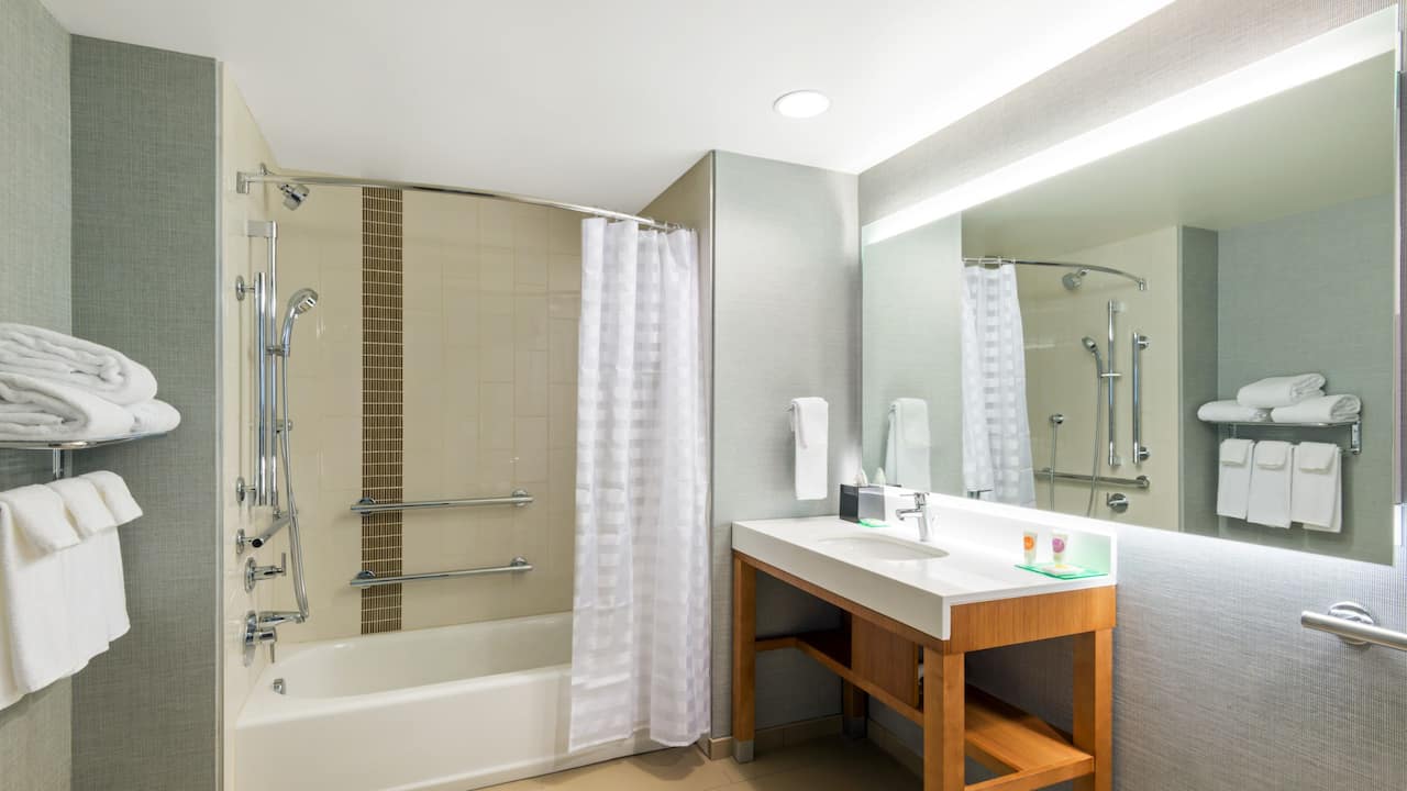 Guestroom bathroom with tub, vanity and large mirror