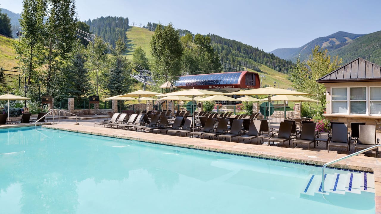 Outdoor pool deck with loungers, sun umbrellas and views of the slopes 
