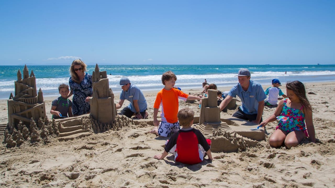 Family building a sandcastles on the beach near hotel