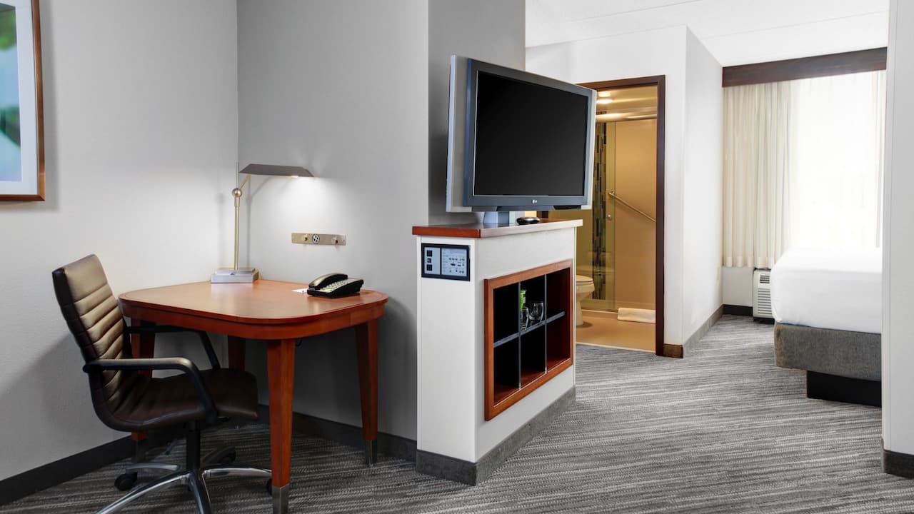A dedicated workspace with chair and desk and living room area with tv at our hotel in Norcross.