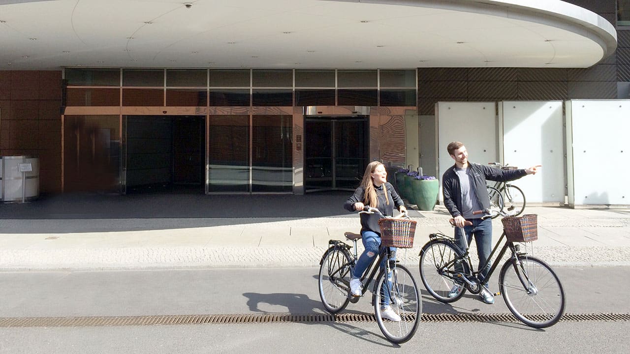 Two cyclists start their bike ride in front of the entrance of Grand Hyatt Berlin
