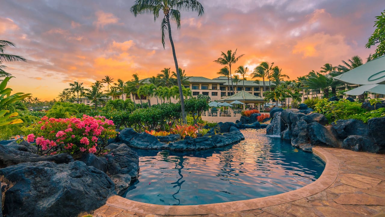 Outdoor river pool with waterfall at sunset at Grand Hyatt Kauai Resort and Spa