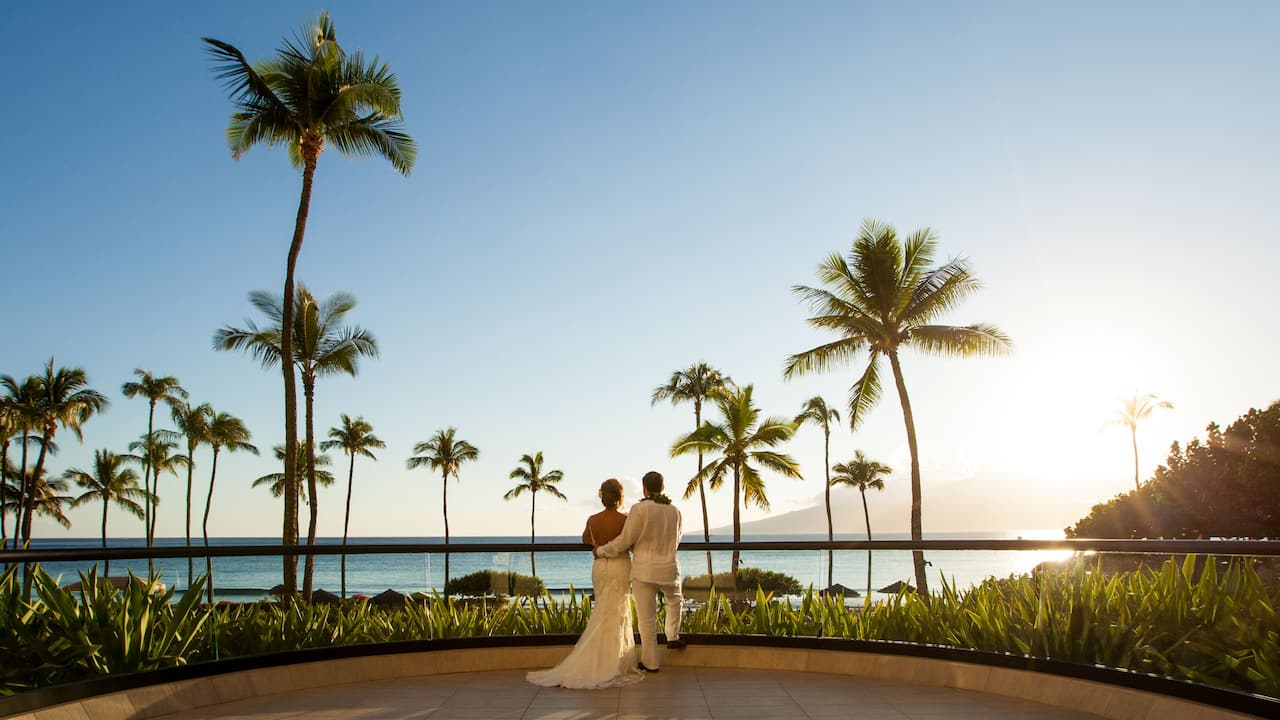 Newlywed couple watching the sunset over the ocean in Maui