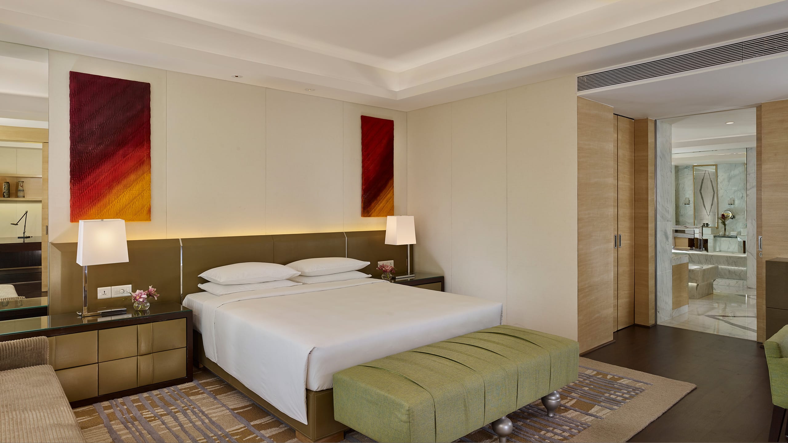 King sized bed between nightstands with lamps in hotel suite