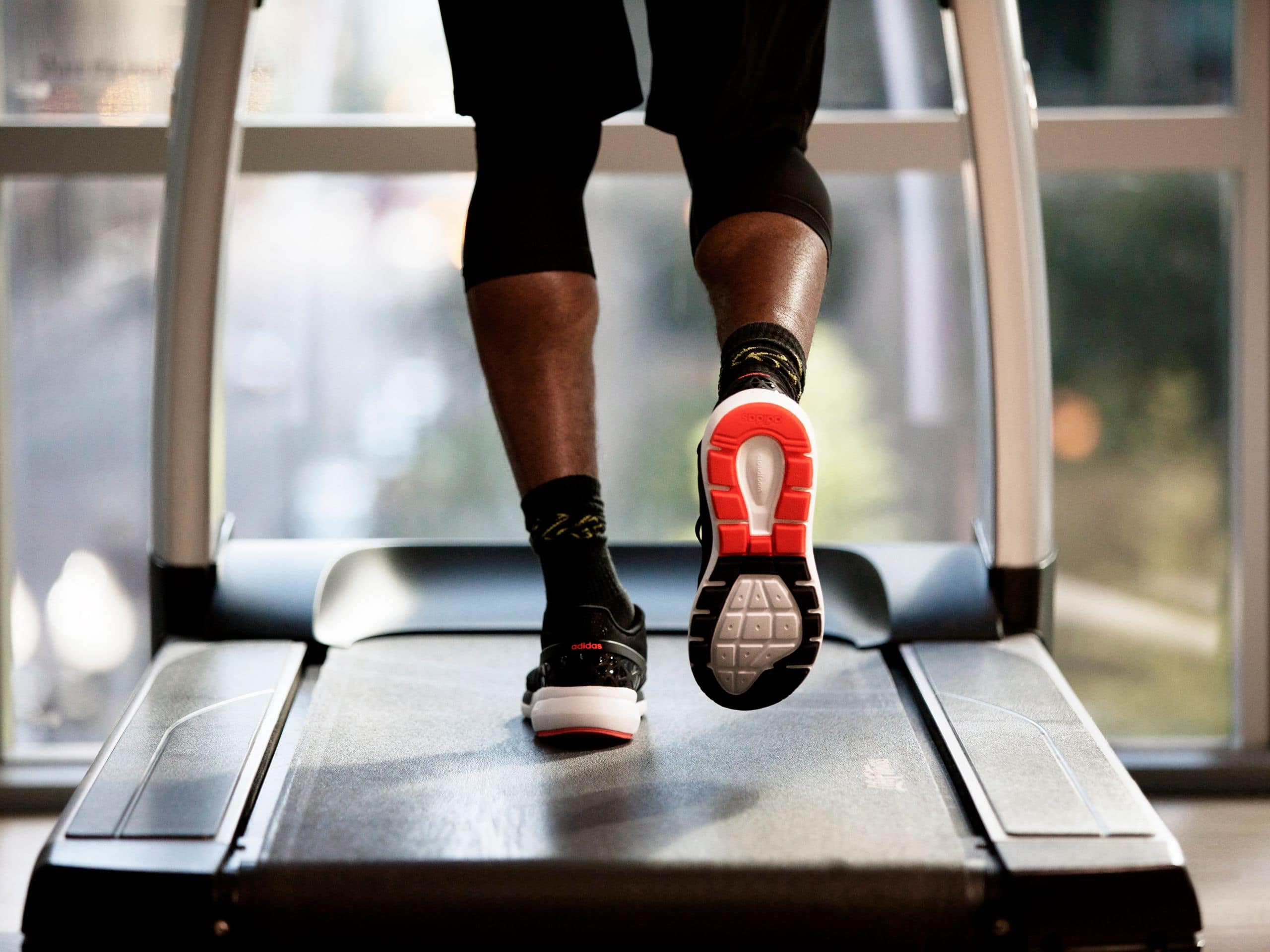 Close up of a person running on a treadmill at Grand Hyatt Al Khobar fitness center, featuring modern gym equipment and a scenic view