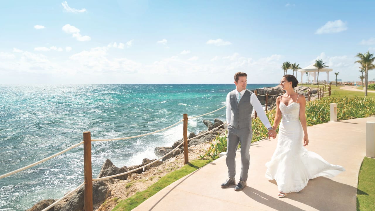 Bride and groom walking above beach