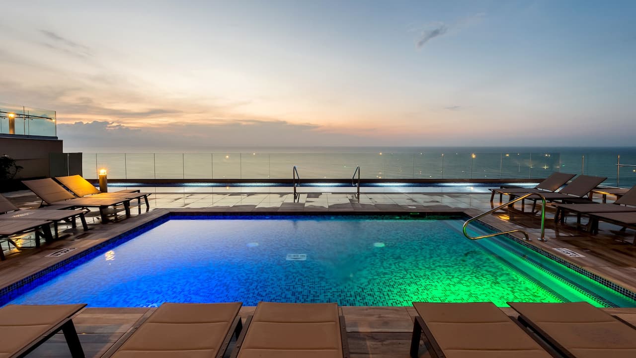 Infinity Pool deck at sunset with loungers and ocean view