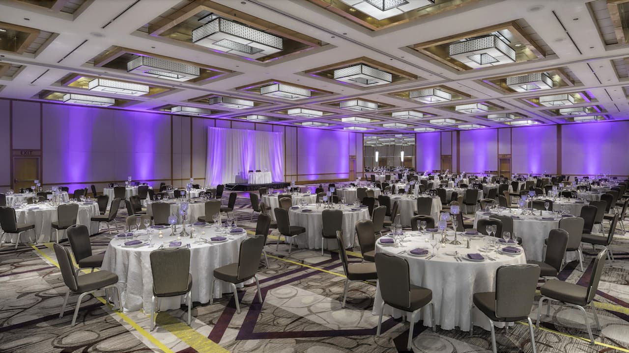 Wedding tables set up with place settings and purple backdrop