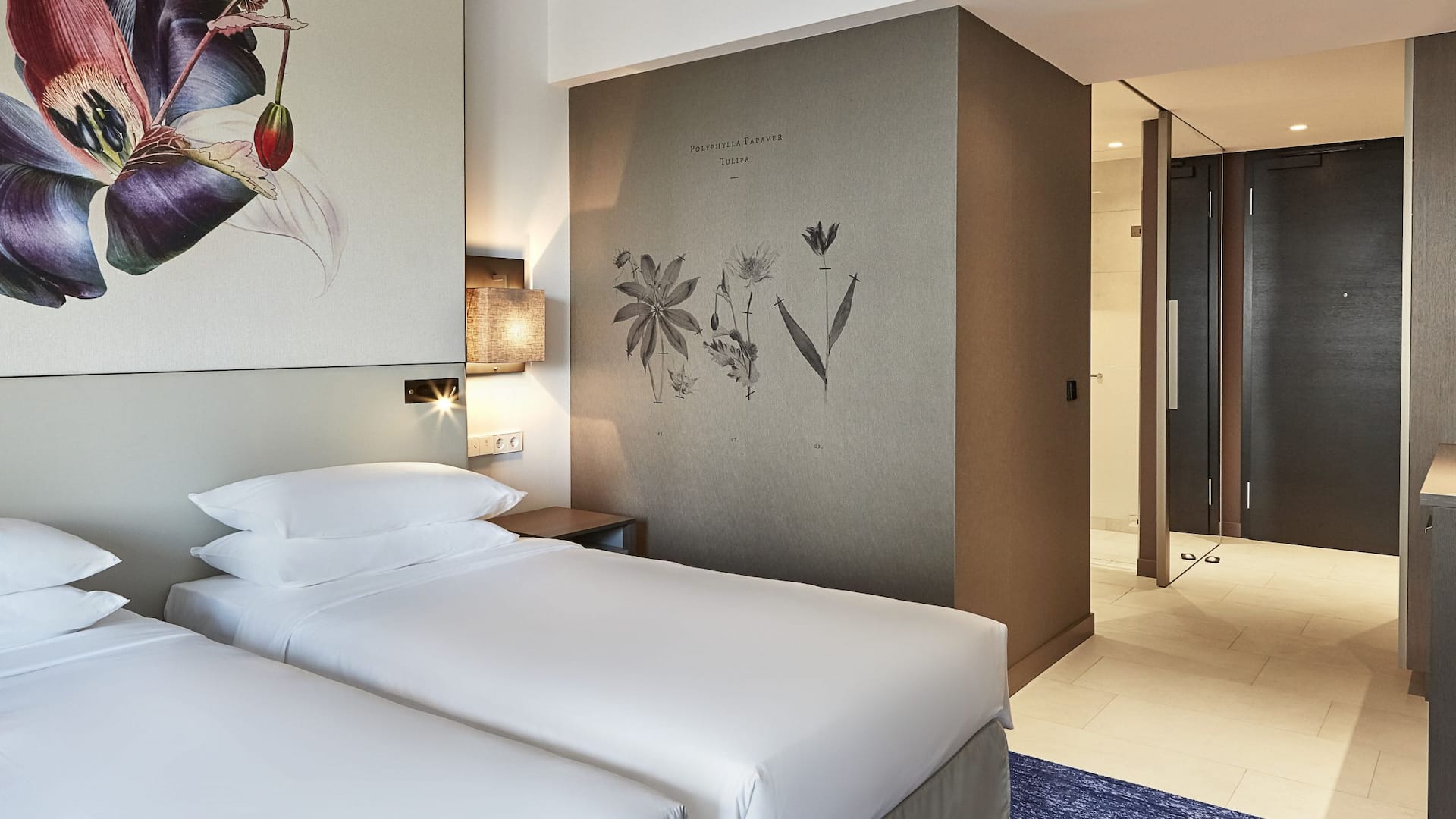 1 von 5 A hotel room in amsterdam with two neatly made twin beds with a botanical headboard.