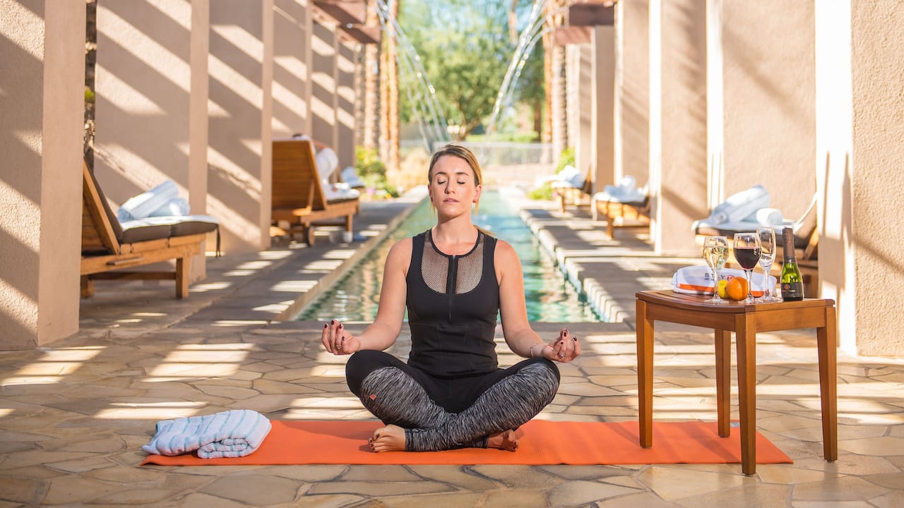 A woman exercising yoga near the outdoor pool offered at Agua Serena Spa