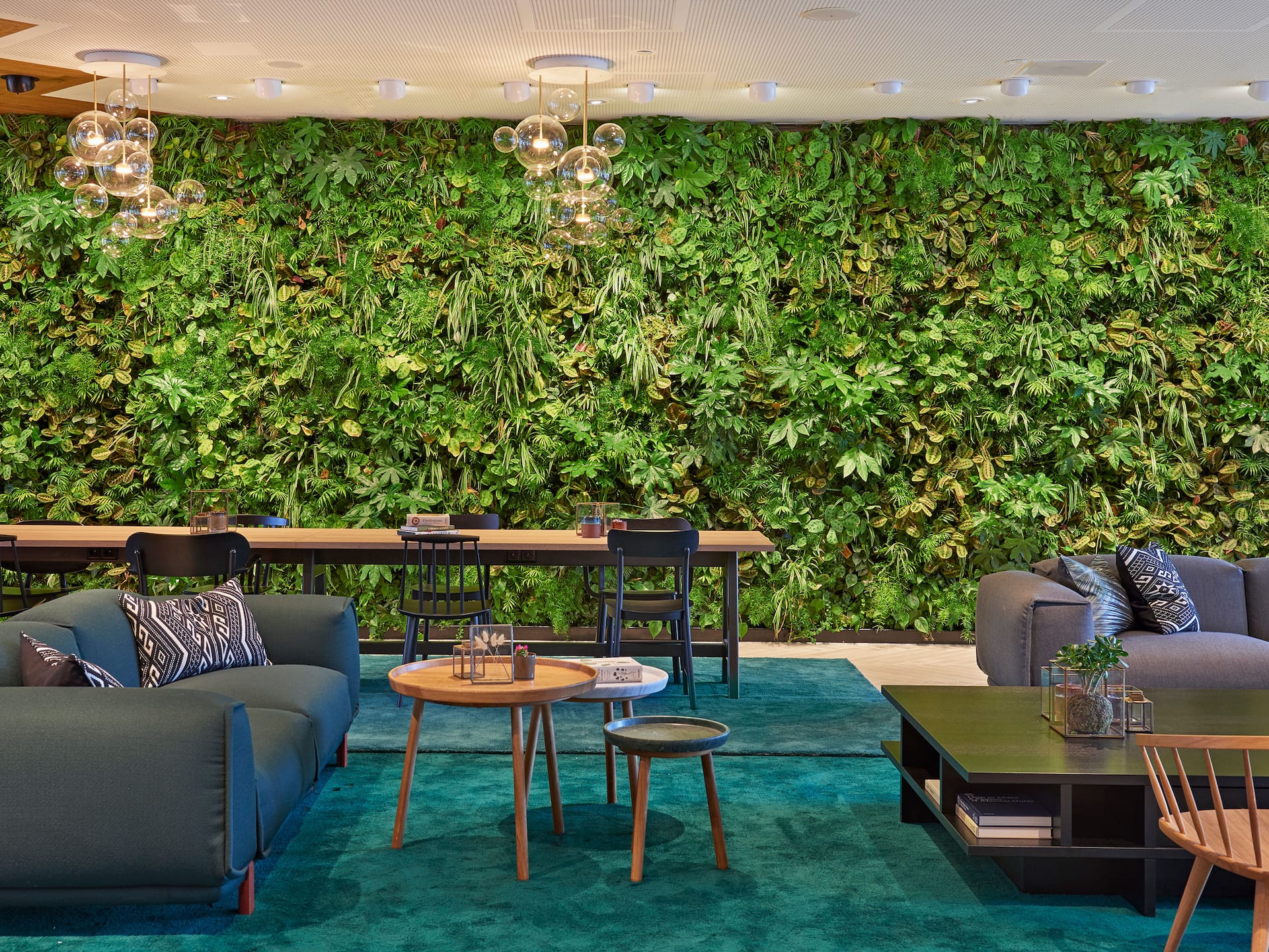 The communal table at the hotel lobby at Hyatt Regency Amsterdam, with a green wall made of plants in the background