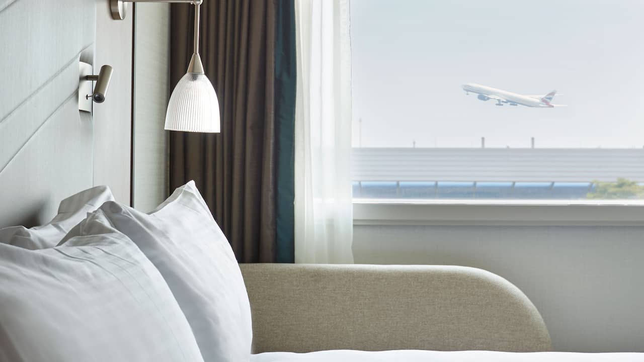 Bed with pillows and a view of a plane taking off