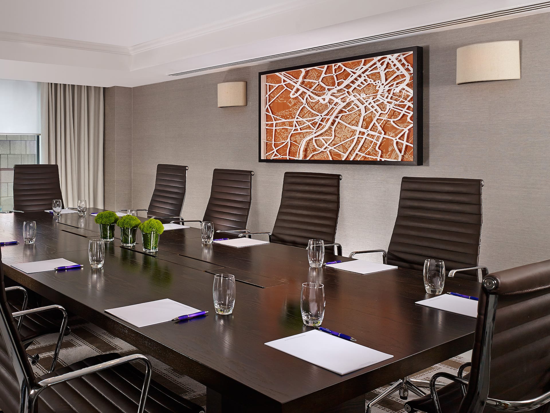 Dark wooden board room at Hyatt Regency Birmingham with comfortable desk chair in a beige room with artwork on the wall.