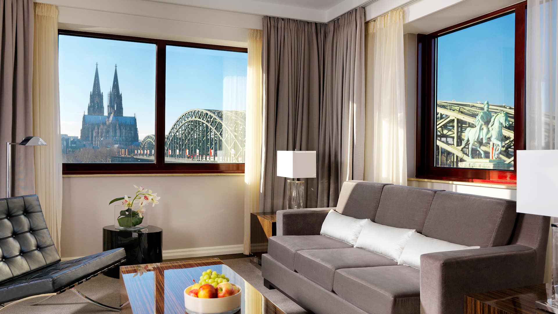 Sofa in front of corner window in suite of Hyatt Regency Cologne with view of cathedral and Hohenzollern Bridge