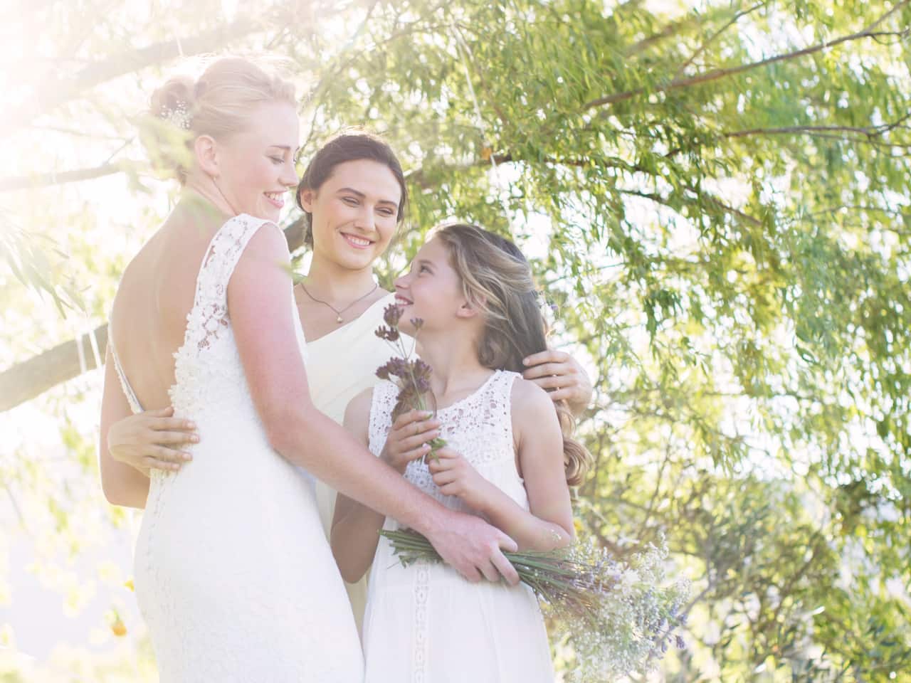 Three bridesmaids smiling and holding flowers