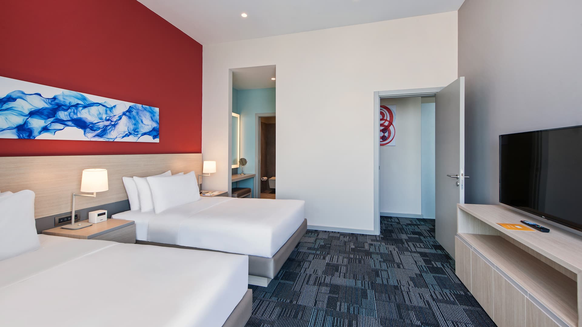 One-bedroom suite in Gebze with two twin beds, TV unit, red headboard wall, modern decor, high ceiling, and partial bathroom view at Hyatt House Gebze, ideal for a comfortable and stylish stay.