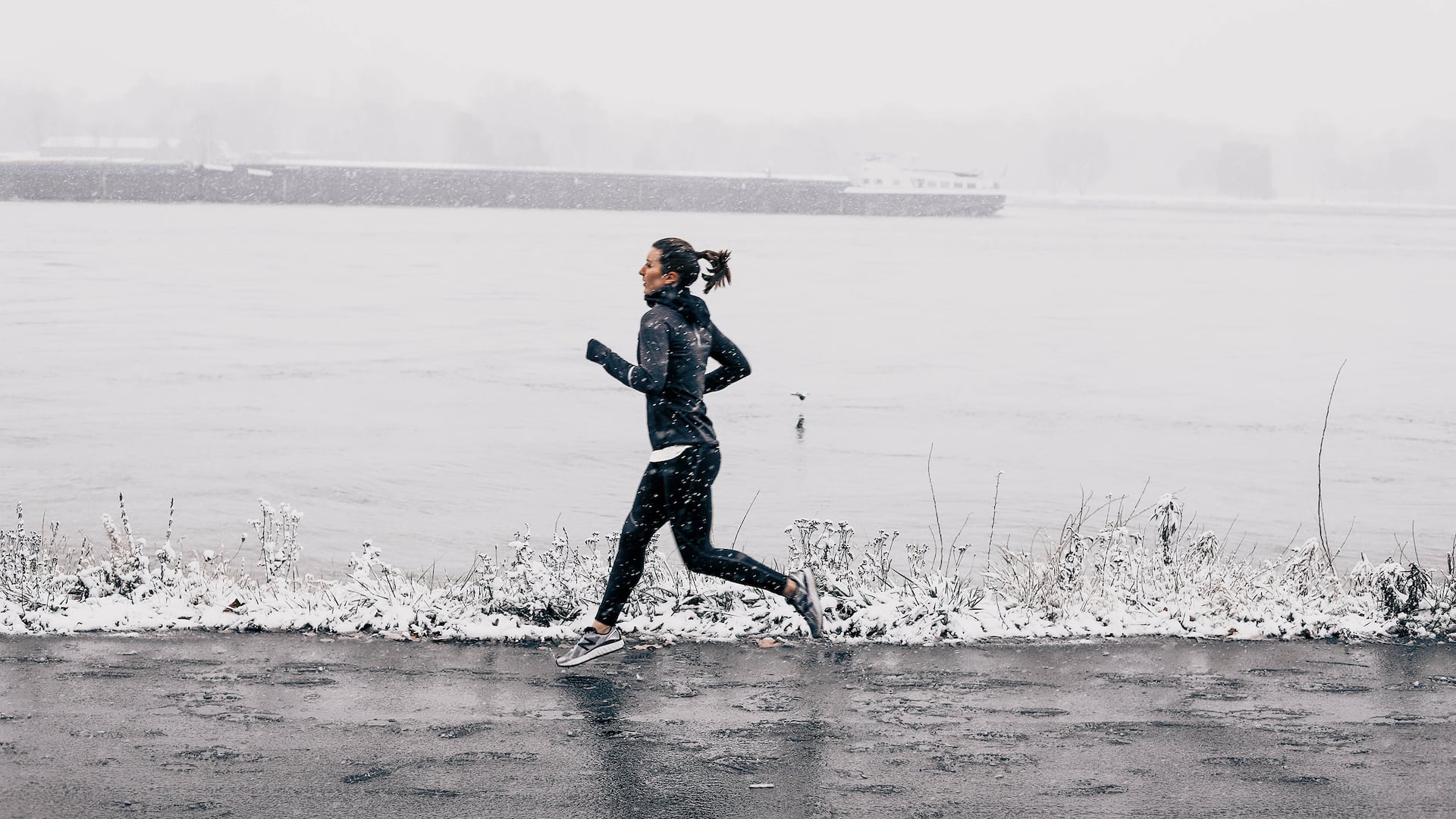 Woman walking in winter weather on the Rhine promenade in front of the Hyatt Regency Mainz