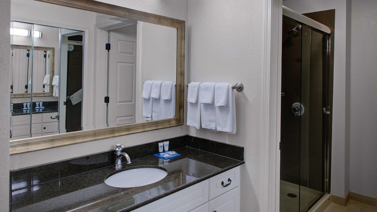 Guest room bathroom sink and mirror with walk in shower at Hyatt House Fishkill / Poughkeepsie