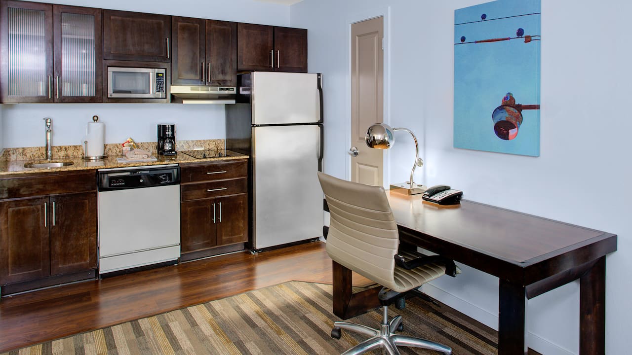 Fully equipped kitchen has fridge with freezer, sink, microwave, and single stove top.