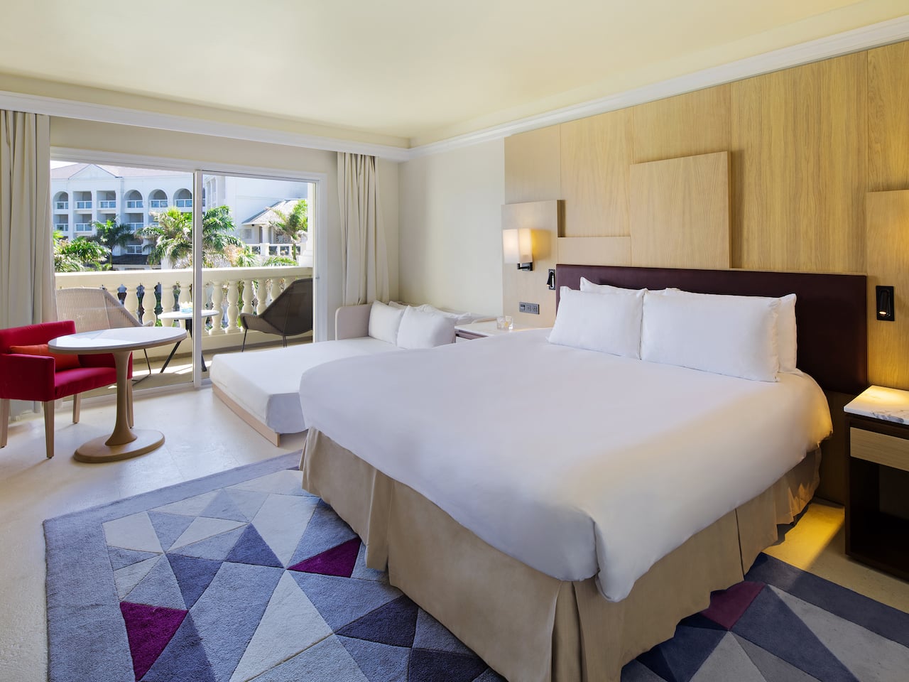 King-sized bed by patio window in resort guestroom