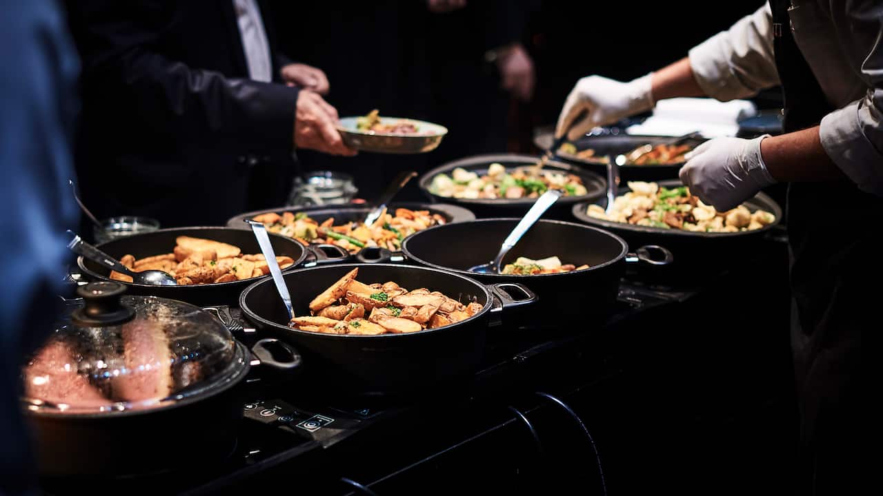 People stand at the buffet and are served