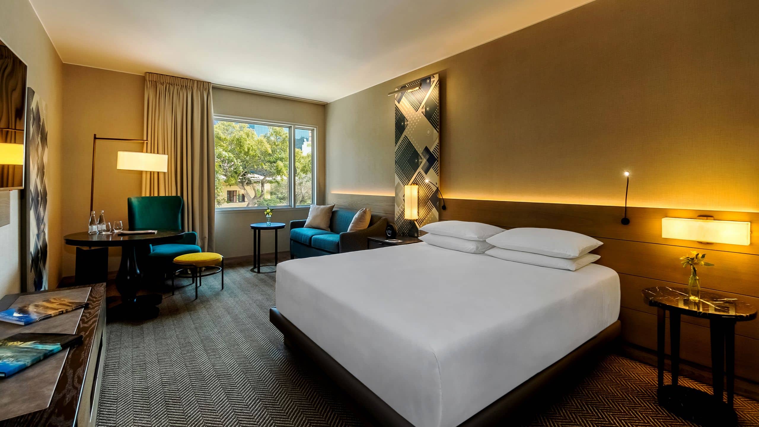 One King Bed Deluxe guest room with large window, sofa, reading chair and lamp