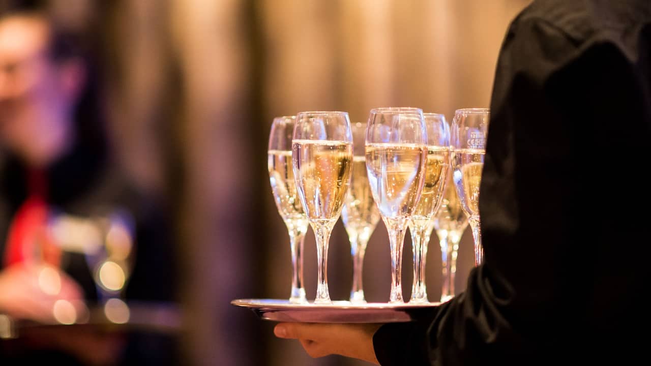 Waiter carries tray with champagne glasses Kellner trägt Tablett mit Sektgläsern
