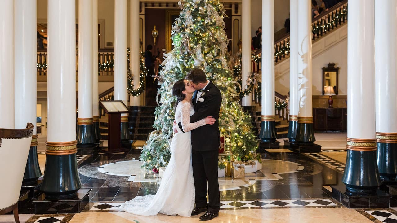 Newlywed couple kissing in the lobby by a Christmas tree