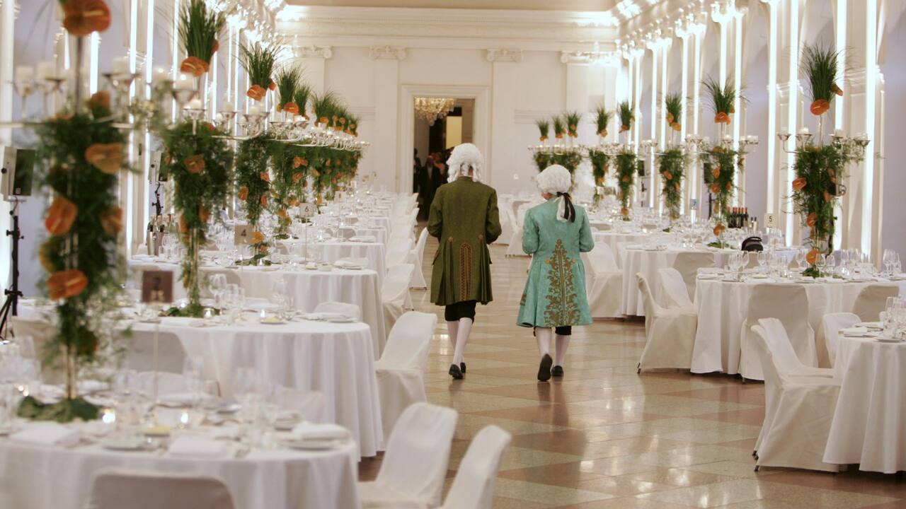 Tables dressed in white at Charlottenburg Palace with service staff in rococo attire