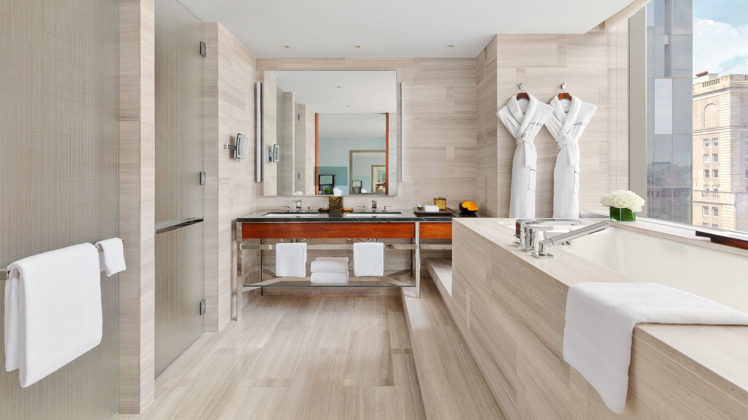 2 of 8 Luxurious bathroom with marble accents, double vanity, and large soaking tub in a hotel suite