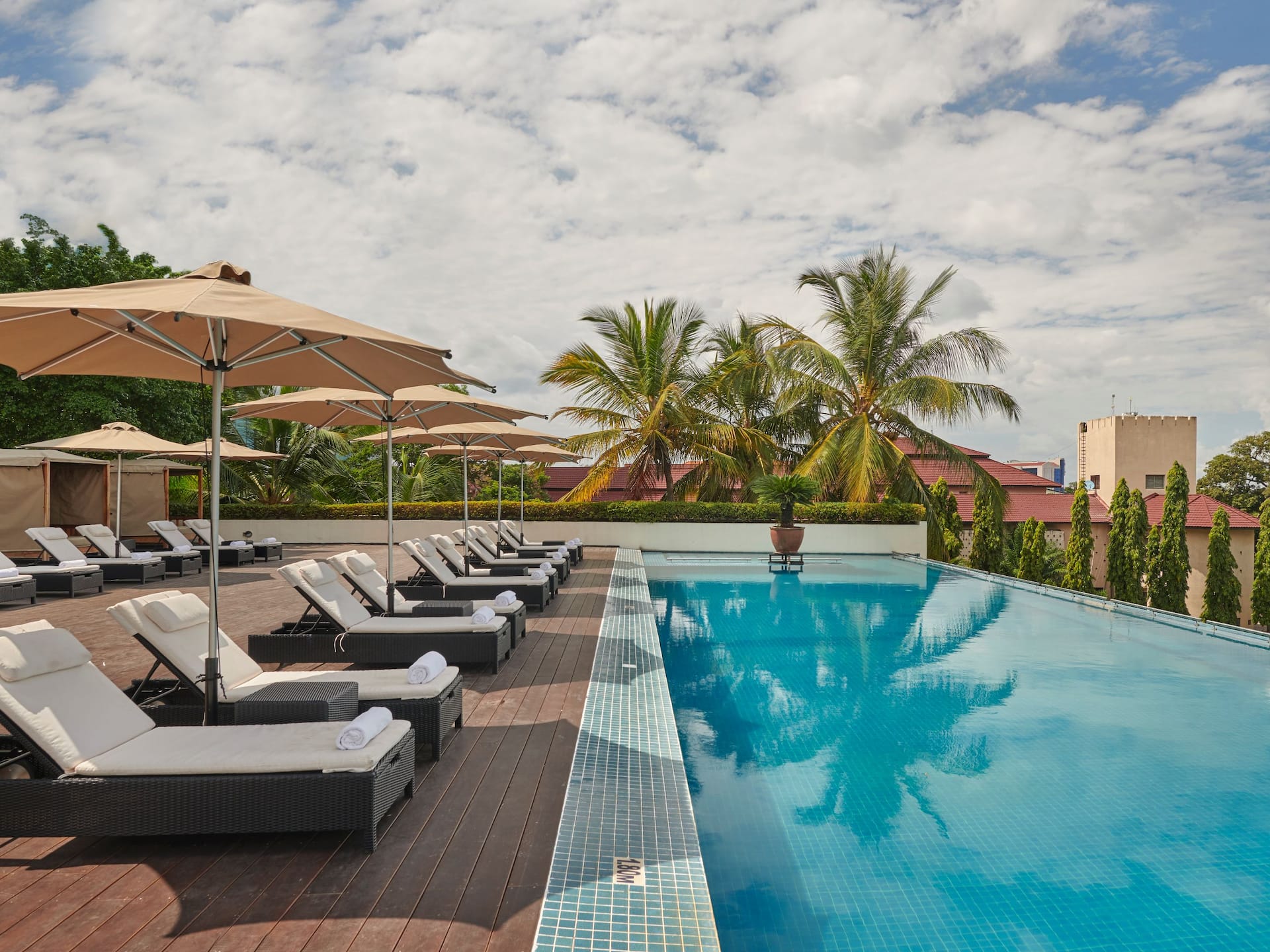 Infinity pool at Hyatt Regency Dar es Salaam, featuring a lounge area with pool beds, umbrellas for shade, and a gazebo with elevated beds.