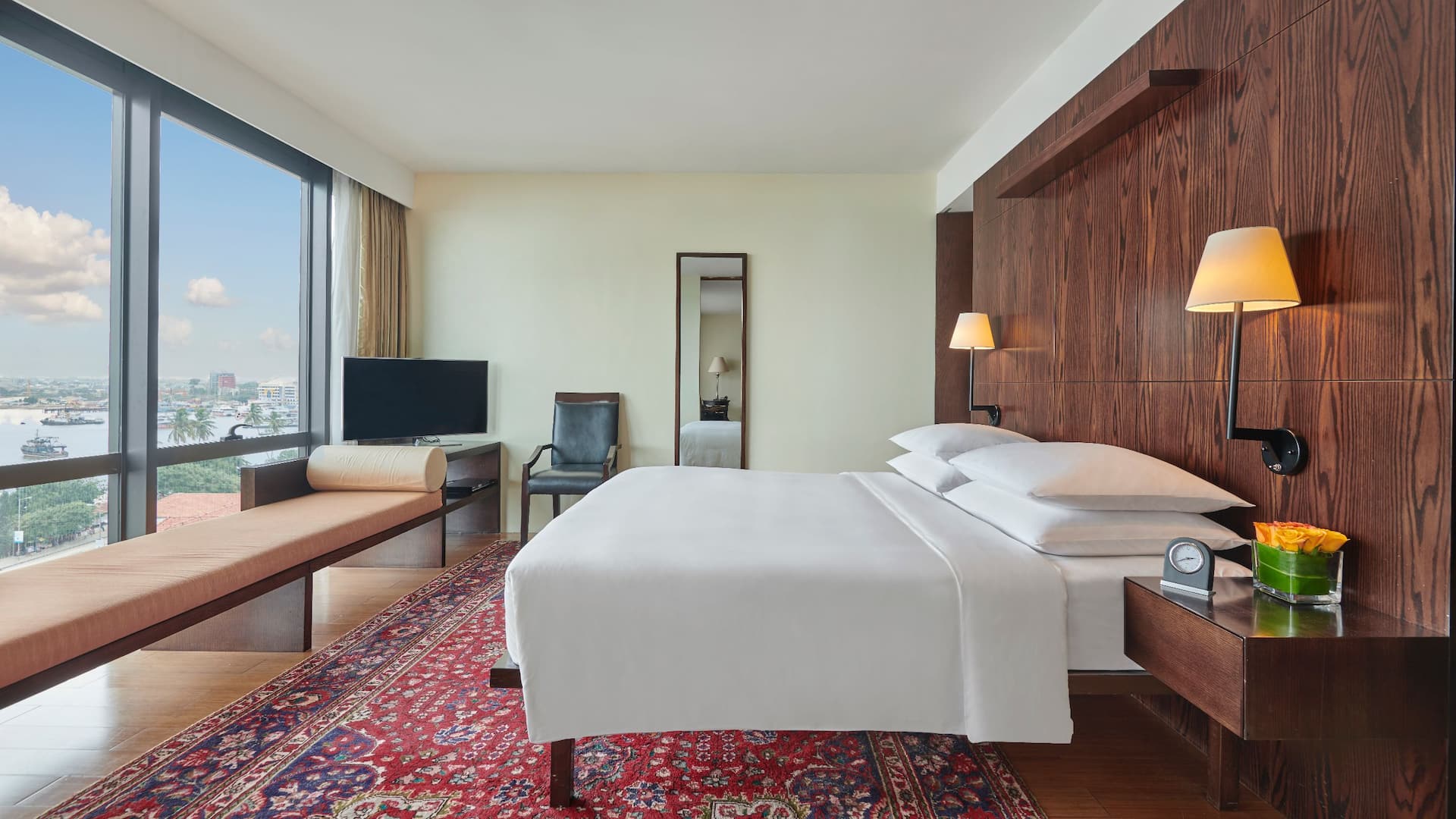 Regency Suite featuring a spacious bed, a rich dark red-toned carpet, and views overlooking the ocean.