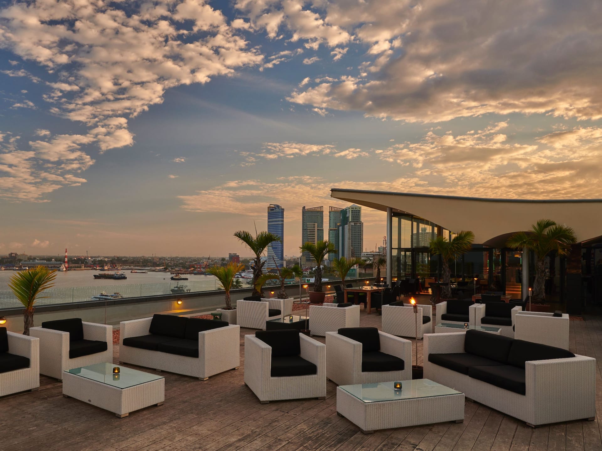 Sunset view from the rooftop of Hyatt Regency Dar es Salaam, featuring stunning views of the ocean and harbor, chair setup, and evening lights.